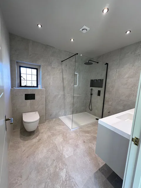 Completed grey bathroom with walk-in shower, vanity unit and recessed lighting