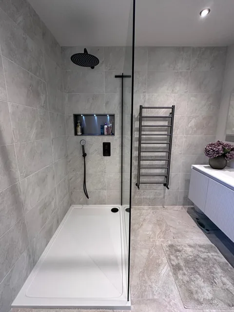 Finished walk-in shower with grey wall finishes, black fittings and recessed lighting