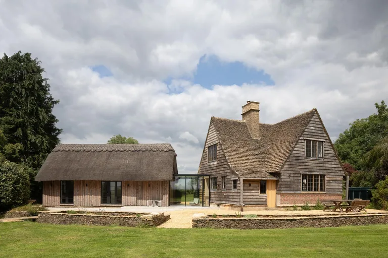 RIBA award-winning Gloucestershire project showing stone home, thatched outbuilding and contemporary extension